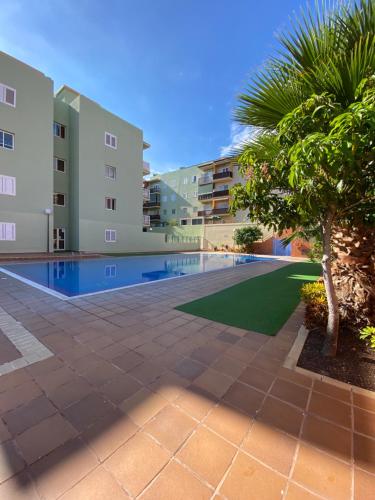 a swimming pool with a palm tree and buildings at Los Menceyes Yaral in Candelaria