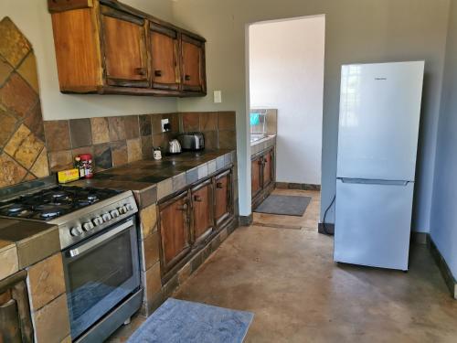 a kitchen with wooden cabinets and a white refrigerator at Rustic Country Cottage in White River