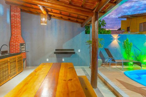 a living room with a wooden table and a swimming pool at Kalug - Chalé Chão de Trancoso Studios in Trancoso