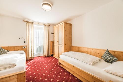 1 dormitorio con 2 camas y alfombra roja en Villa Scherlin, en Ortisei