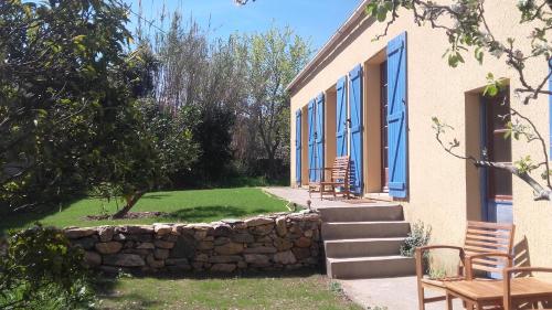 - un bâtiment avec des fenêtres bleues et un mur en pierre dans l'établissement Casa di Ceppo, à Patrimonio
