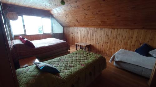 1 dormitorio con 2 camas en una cabaña de madera en Hostal Casa Damasco, en Ancud