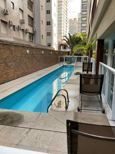 a swimming pool on the side of a building at Estanconfor Flat Garagem e limpeza diária in Santos