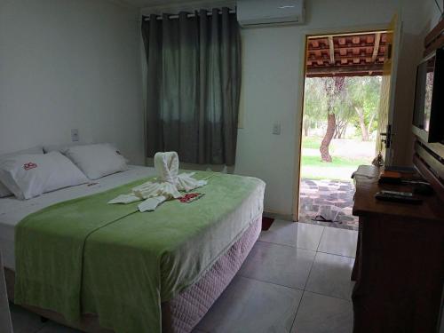 a bedroom with a bed with a green blanket and a window at POUSADA SAKURA in Patrimônio São Sebastião