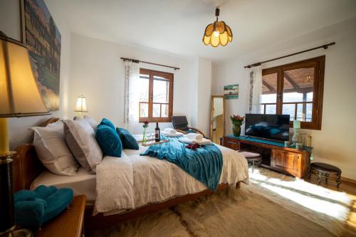 a bedroom with a bed with blue pillows and a television at Villa Pallas 