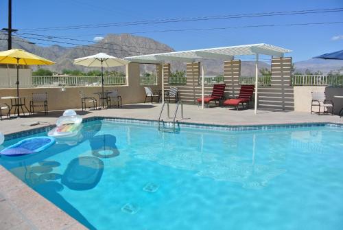 - une piscine avec des chaises et des parasols dans un complexe dans l'établissement Borrego Springs Motel, à Borrego Springs