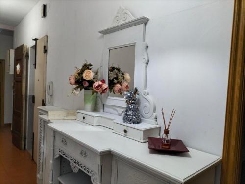 un tocador blanco con espejo y flores. en Appartamento con terrazza in Santa Maria Novella, en Florencia