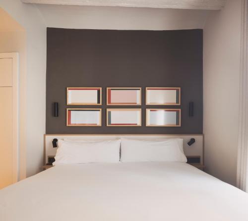 um quarto com uma cama branca com quatro fotografias na parede em Anderson City Flats em Valência
