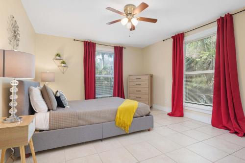 a bedroom with a bed with red curtains and a ceiling fan at Cordova Dream Upper in St. Augustine