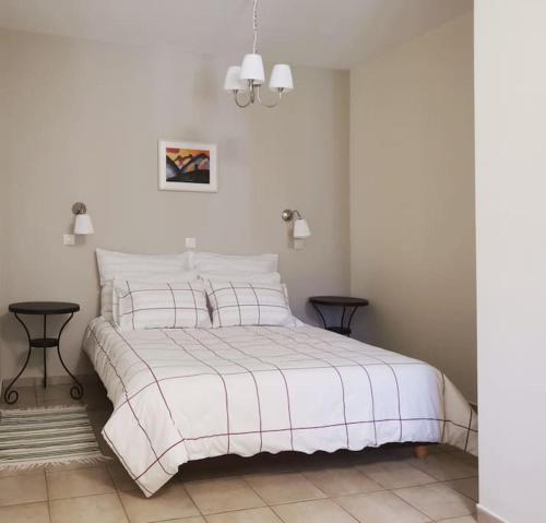1 dormitorio blanco con 1 cama blanca y 2 mesas en Ξενώνας ΙΙ σε αγροικία με τζακι, en Kalavrita