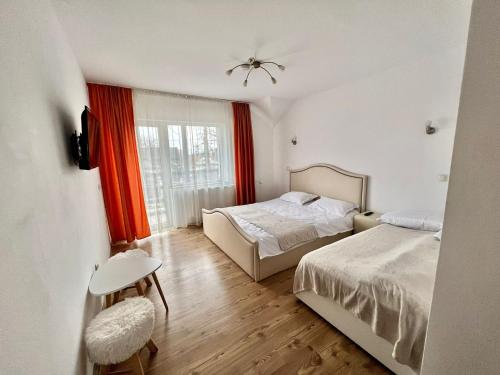 1 Schlafzimmer mit 2 Betten und einem Fenster mit roten Vorhängen in der Unterkunft Garden Villa in Braşov