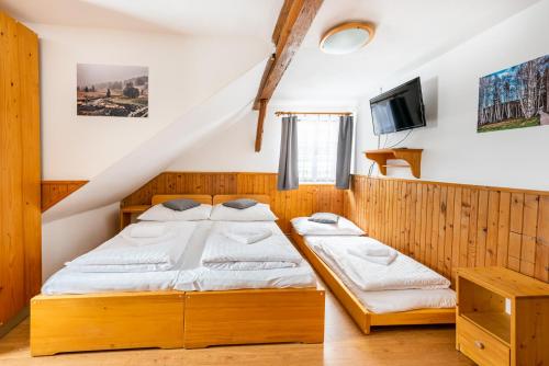 1 dormitorio con 2 camas y TV en Penzion Černý vlk, en Kvilda