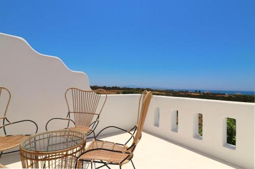 a group of chairs on a balcony with a view of the ocean at The Nine Graces - Kastraki Villas with Private Swimming Pool in Kastraki Naxou