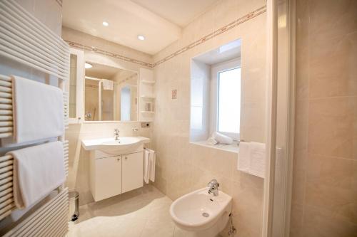 a white bathroom with a sink and a toilet at Central Apartments Cristlpek in Ortisei