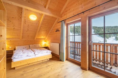 ein Schlafzimmer in einem Blockhaus mit einem Bett und einem Fenster in der Unterkunft Veselý Svišť Chalet Lachtal in Lachtal