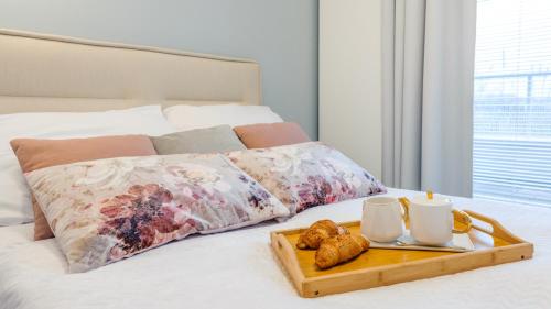 een dienblad met croissants en mokken op een bed bij Apartament Lux Tukan B004, Polanki Aqua - Holiday City in Kołobrzeg