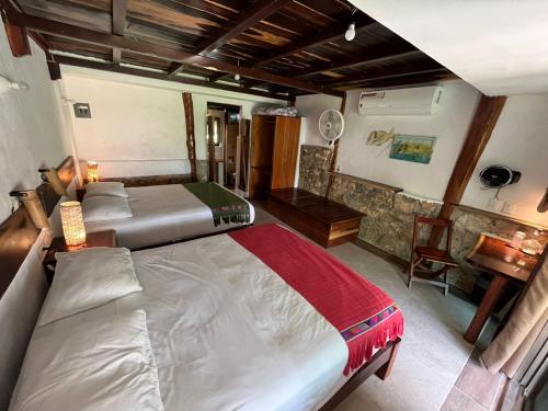 a bedroom with two beds and a table and a desk at Casa Lamat in Bacalar