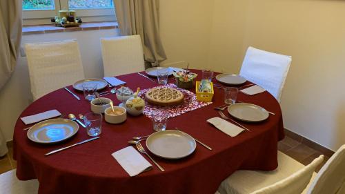 a table with a red table cloth with plates and glasses at Altra Meta b&b in Gubbio