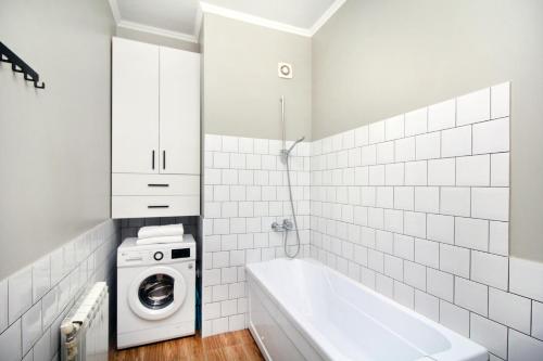 y baño blanco con lavadora y bañera. en Perfect spacious apartment en Almaty