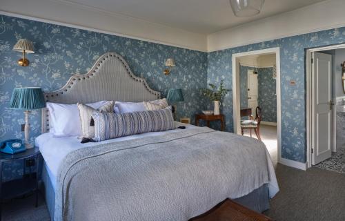 a bedroom with a large bed with blue wallpaper at Stanwell House in Lymington