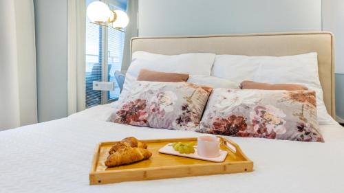 a tray with a plate of food on a bed at Apartament Lux Tukan B005 Polanki Aqua - Holiday City in Kołobrzeg