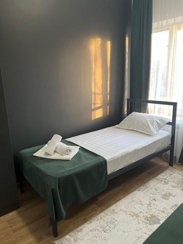 a bed in a room with a green blanket and a bed with avertisement at A Hotel Bishkek in Bishkek