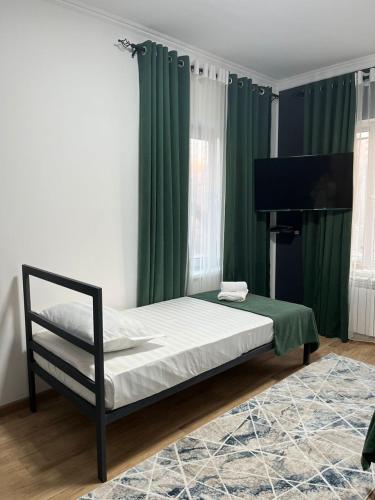 ein Schlafzimmer mit einem Bett mit grünen Vorhängen und einem Klavier in der Unterkunft A Hotel Bishkek in Bischkek