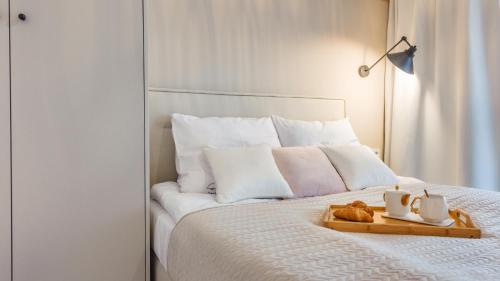 a bedroom with a white bed with a tray of food on it at Apartamenty Tukan- Polanki Aqua - Holiday City in Kołobrzeg