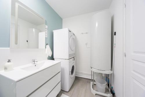 W białej łazience znajduje się pralka i suszarka. w obiekcie L'Émeraude w mieście Malesherbes