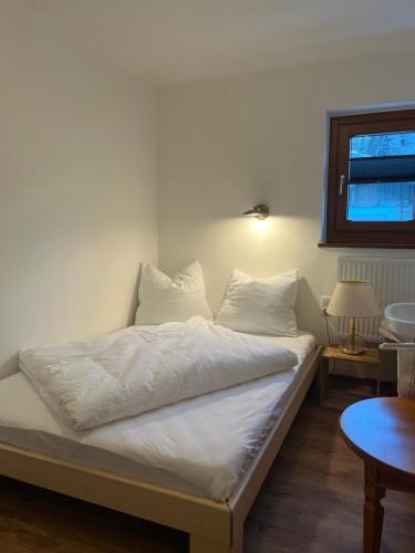 a bed with white sheets and pillows in a room at Ferienwohnung Ingrid Hörbiger in Mittersill