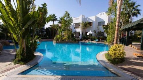 a large blue swimming pool with palm trees and a building at لدينا مكتب عقارات في قرية دلتا شرم We have a real estate office in Delta Sharm in Sharm El Sheikh