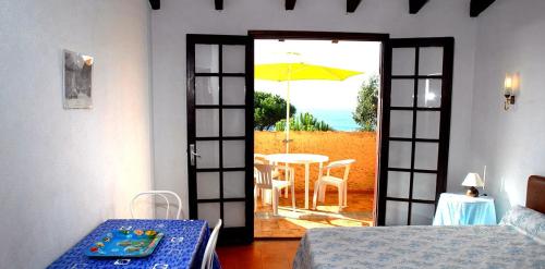 Habitación con puerta que da a una mesa con sombrilla en Motel Logis d'Abartello, en Olmeto