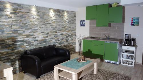 ein Wohnzimmer mit einem schwarzen Ledersessel und grünen Schränken in der Unterkunft Appartement Ursula Eck in Bergisch Gladbach