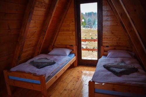 2 camas en una cabaña de madera con ventana en Vikendica Tromedja Pale, en Pale