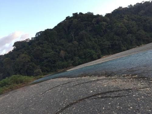 a hillside with a body of water and a mountain at Cabina equipada cerca de río y montañas Tulín Azul in Tulín