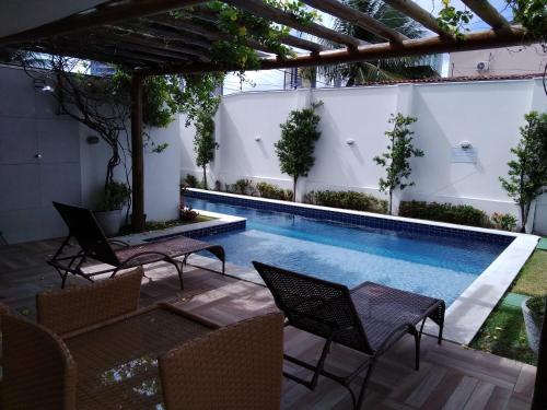 un patio con piscina, sillas y pérgola en Flat com vista panorâmica na melhor localização, en Natal