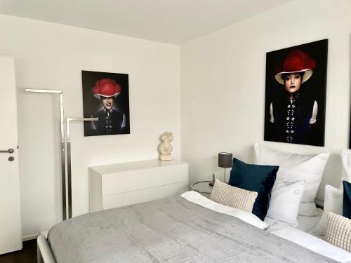 een slaapkamer met twee schilderijen van een man met een hoed bij Modernes Apartment mit traumhaftem Sunset Blick in Baden-Baden