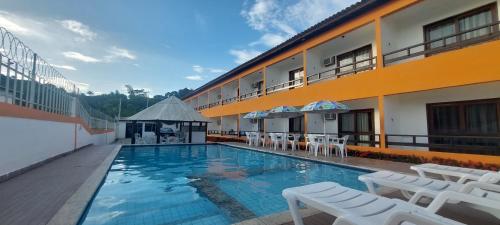 um hotel com piscina com cadeiras e um prédio em Pousada Porto Feliz em Porto Seguro