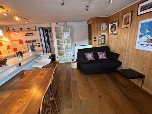 a living room with a black couch and wooden floors at Appartement 2pieces Hyper Centre Les Houches, proche Chamonix in Les Houches