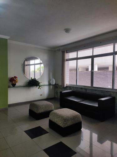 a living room with a black couch and a mirror at Lindo apto vista lateral do mar Itararé São Vicente in São Vicente