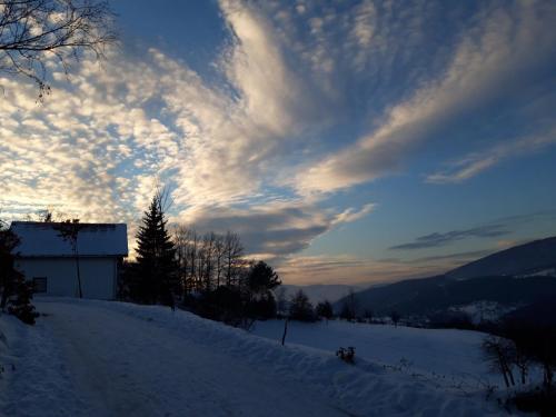 a cloudy sky above a snow covered hill with trees at The Village House Zlatar in Nova Varoš