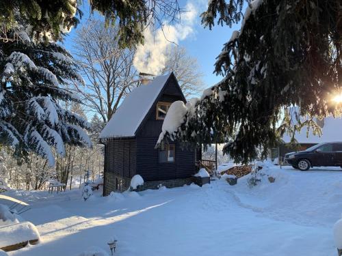 a small cabin with a chimney in the snow at Chata 1-Padesátka in Bedřichov