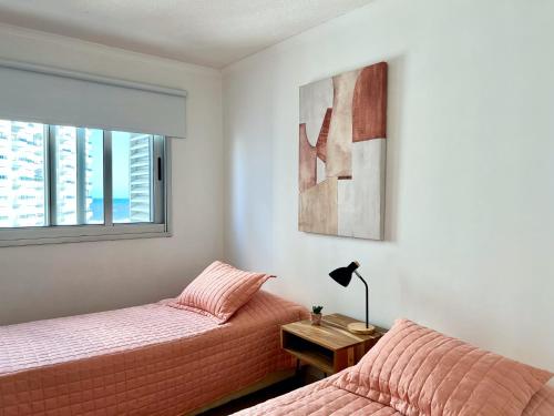1 dormitorio con 2 camas y ventana en South Beach Apartment, en Punta del Este