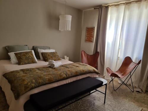 a bedroom with a bed and two chairs and a window at La Maison de Lyna - Suites de charme intra-muros avec parking & autonomie in Aigues-Mortes