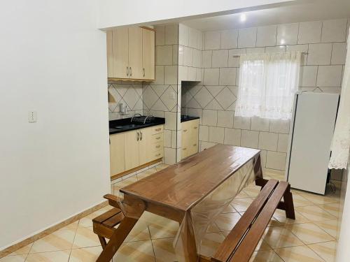 a kitchen with a wooden table and a refrigerator at Suites da Rota - Pomerode SC in Pomerode