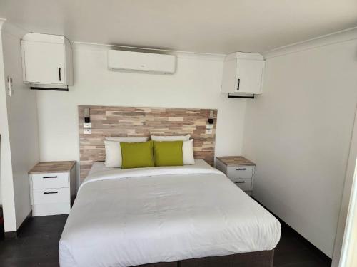 1 dormitorio con 1 cama blanca grande con almohadas verdes en Budget on the Lake, en Hamilton