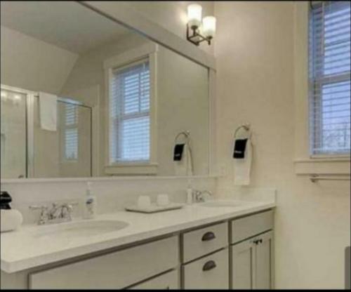 a white bathroom with two sinks and a mirror at The Coastal Inn in Cellardyke