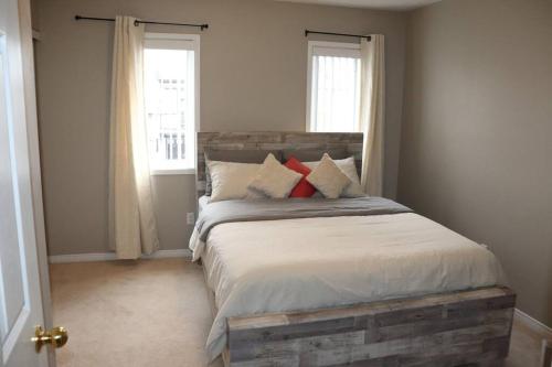 a bedroom with a bed with a wooden headboard and two windows at Entire 4 bed room detached residential home in Ajax