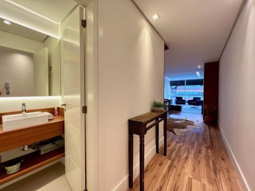 ein Bad mit einem Waschbecken und einem Spiegel in der Unterkunft Apartamentos Gartenberg no CENTRO by Achei Gramado in Gramado
