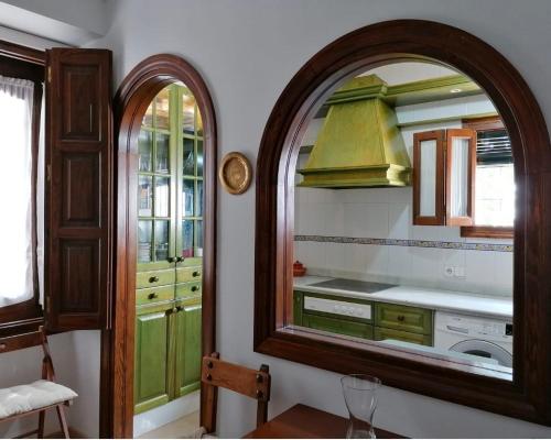 cocina con armarios verdes y espejo en Casa Rural Torre del Agua. Un lugar con encanto., en Osuna